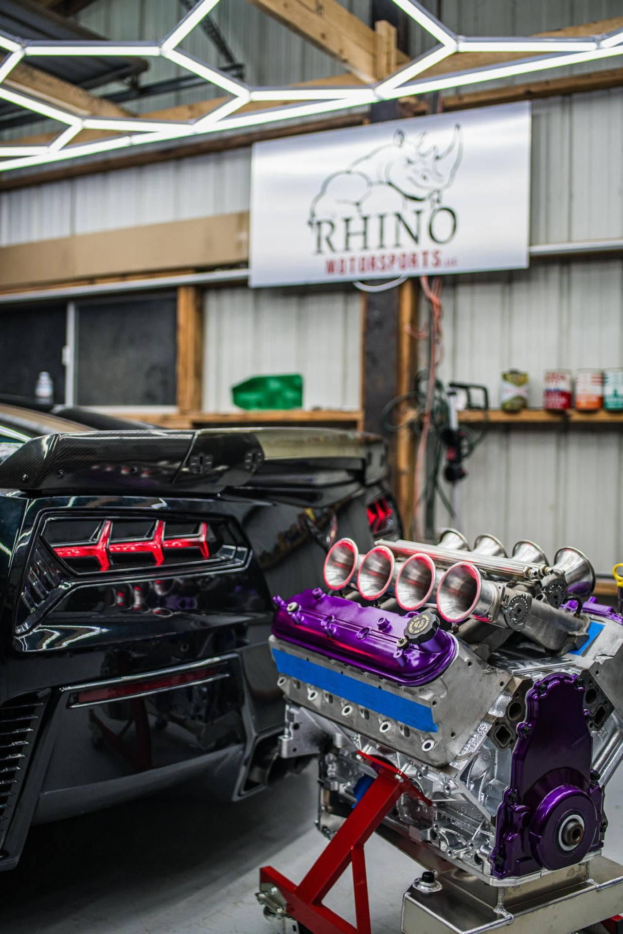 Rhino Motorsports shop with a black performance car and purple engine on a stand